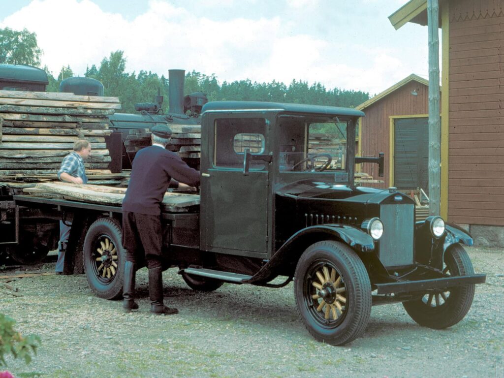 Bild eines restaurierten Volvo-Lastwagen vom Typ LV4 aus dem Jahr 1928; die Szene zeigt die Beladung mit Holzbrettern durch einen Arbeiter und den Fahrer