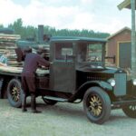 Bild eines restaurierten Volvo-Lastwagen vom Typ LV4 aus dem Jahr 1928; die Szene zeigt die Beladung mit Holzbrettern durch einen Arbeiter und den Fahrer