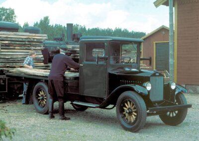 Bild eines restaurierten Volvo-Lastwagen vom Typ LV4 aus dem Jahr 1928; die Szene zeigt die Beladung mit Holzbrettern durch einen Arbeiter und den Fahrer