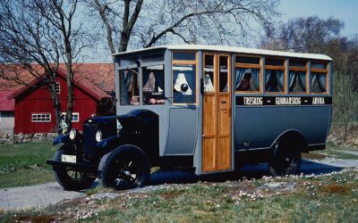 Bild eines restaurierten Volvo-Omnibusses auf Basis des Lkw-Modells LV4 aus dem Jahr 1928; der Bus fährt auf einer Schotterstraße vor einer Siedlung