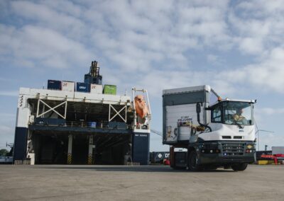 Volvo elektrifiziert auch Off-Highway-Fahrzeuge Batterieelektrisch angetriebener RoRo-Traktor von MOL in einem Hafen, im Hintergrund ein angelandetes Fährschiff